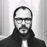 Christian Nascimento - A man with short hair and glasses dressed in a black jacket